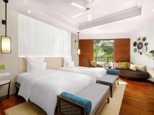 a bedroom with two beds and a couch at Pullman Danang Beach Resort in Danang