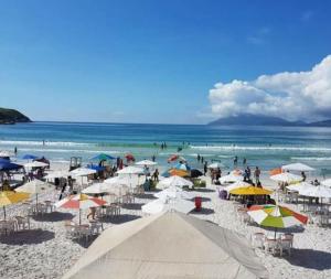 a group of people on a beach with umbrellas at Praia do Forte - AP DA PAZ in Cabo Frio