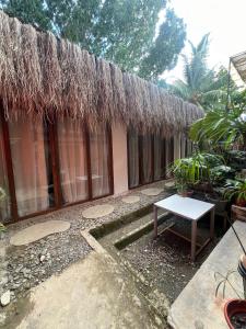 a building with a thatched roof with a table in front at Kundiman Siargao, General Luna in General Luna