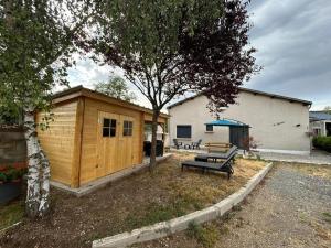 a wooden cabin with a bench and a tree at Le chaumet in SAINT DENIS EN MARGERIDE