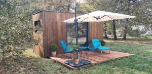 a couple of chairs and an umbrella on a deck at Modulbois studio castelnau in Castelnau-de-Médoc