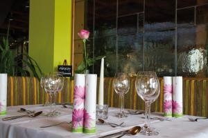 a table with wine glasses and a pink rose at Hotel Promenade in Bad Steben