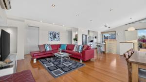 a living room with a red couch and a table at Nautilus - Modern Lakeside Escape in Lakes Entrance