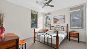 a bedroom with a bed and a desk and windows at Nautilus - Modern Lakeside Escape in Lakes Entrance