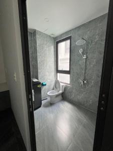 a bathroom with a toilet and a window at Flower Apartment in Buôn Enao