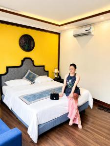 a woman sitting on a bed in a hotel room at Aurora Hotel SaPa in Sapa