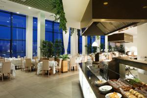 a restaurant with white tables and chairs and windows at Sandos Papagayo in Playa Blanca