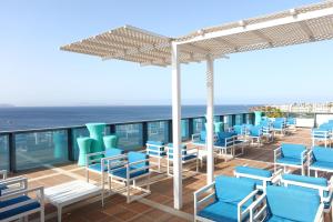 a deck with chairs and tables and the ocean at Sandos Papagayo in Playa Blanca