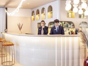 two men in suits sitting at a bar at Novotel Marseille Centre Prado Vélodrome in Marseille