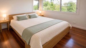 a bedroom with a large bed with two windows at Anchor at Bawley in Bawley Point +8 photos