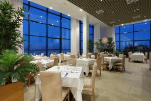 a restaurant with white tables and chairs and large windows at Sandos Papagayo in Playa Blanca