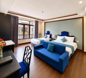 a hotel room with two beds and a blue couch at Aurora Hotel SaPa in Sapa