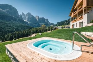 una bañera de hidromasaje en una terraza con montañas al fondo en Lüch de Costa en Colfosco