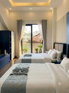 two beds in a room with a large window at An Phát Villa Đà Lạt in Da Lat
