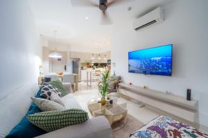 a living room with a couch and a tv on a wall at Cassia Apartment 1 in Bang Tao Beach