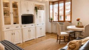 eine Küche mit weißen Schränken und einem Tisch mit einem Fernseher in der Unterkunft QuickHome Monviso in Santhià