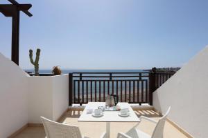 a table and chairs on a balcony with the ocean at Sandos Papagayo in Playa Blanca