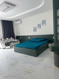 a bedroom with a blue bed in a room with chairs at Flower Apartment in Buôn Enao
