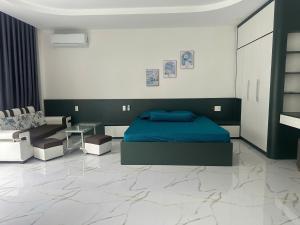 a bedroom with a blue bed and a couch at Flower Apartment in Buôn Enao