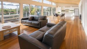 a living room with a leather couch and a table at Anchor at Bawley in Bawley Point
