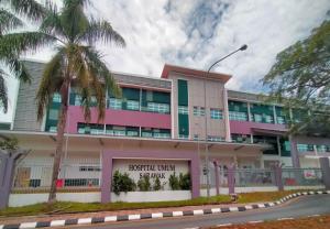 a pink building with a palm tree in front of it at Point Stay GH in Kuching +7 photos