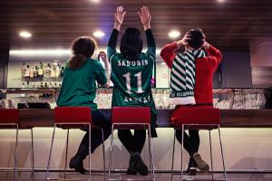 tres personas sentadas en un bar con las manos en alto en Ibis Kaunas Centre, en Kaunas