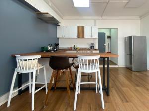 a kitchen with a counter with three chairs and a refrigerator at El Martín Pescador in Osorno +17 photos