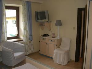 a living room with a tv and a chair at Pension Landhaus Ingrid in Loich