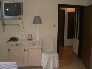 a room with a chair and a tv on a cabinet at Pension Landhaus Ingrid in Loich +16 photos