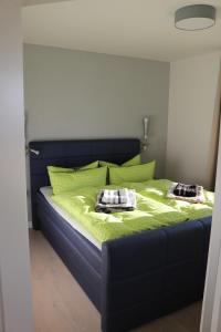 een slaapkamer met een bed met groene lakens en kussens bij Ostseezauber in Ostseebad Sellin