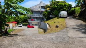 a house with a van parked on the side of a road at Harmony Caraibes in Le Robert