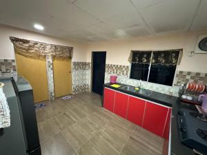 an empty kitchen with red cabinets and a sink at Kannan homestay in Kamunting