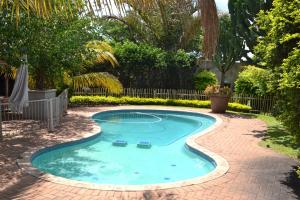 a small swimming pool with a brick walkway around it at Paradise Creek Lodge in Malelane