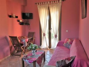 a living room with pink walls and a table and a couch at The Olive Tree House in Kompítsion