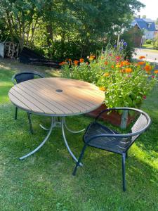 a wooden table and two chairs in a yard with flowers at Litet hus utanför Luleå in Luleå