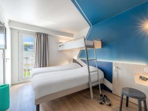 a room with two beds and a blue wall at Ibis budget Chambéry Centre Ville- Hôtel Rénové in Chambéry