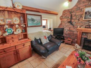 a living room with a leather couch and a stone wall at Piggery Cottage in Wigton