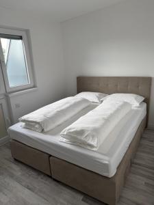 a large bed with white sheets and pillows at Stan centar Gračanica in Gračanica