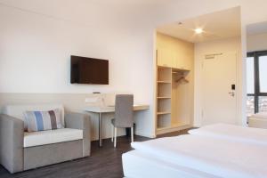 ein Hotelzimmer mit 2 Betten, einem Schreibtisch und einem TV in der Unterkunft Viva Hotel Lübeck in Lübeck