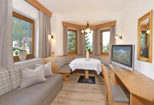 a living room with a couch and a table with a television at Apparthotel Thalerhof in Mayrhofen