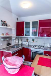 kuchnia z czerwonymi szafkami i drewnianym stołem w obiekcie Apartment Flores w mieście Osijek