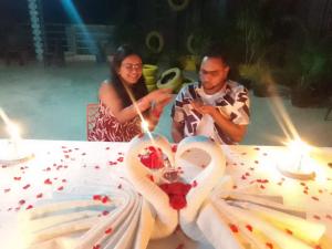 a man and a woman sitting at a table with a cake at Andaman Beach Resort in Shādipur