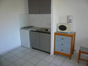 une cuisine avec un évier et un micro-ondes sur une table dans l'établissement Les Marines de Morian, à Moriani-Plage