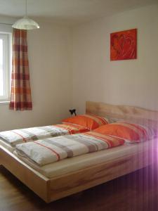 a bedroom with a large bed with orange pillows at Biohof Stockinger in Kirchbach