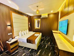 a hotel room with a bed and a flat screen tv at Presken Hotel Castle, Opebi Lagos in Lagos