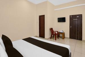 a hotel room with a bed and a chair at Super Hotel O Temple Road Vemulavada in Karīmnagar +30 photos