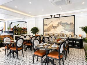a dining room with tables and chairs and a large painting at Anara Sapa Hotel & Coffee in Sapa
