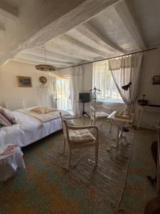 a bedroom with a bed and chairs and a tv at La vallée des grottes in Saint-Germain-sur-Vienne