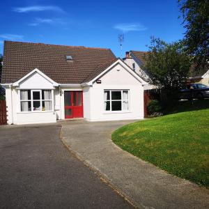 a white house with a red door and a driveway at Letterkenny View in Letterkenny