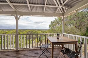 a table and chairs on a deck with a view at Hillview - Spacious Bushland Haven with Resort Access in Yallingup